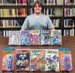 Mason Kivler Sitting In Front Of Some Of His Collection Of Comics And Figurines