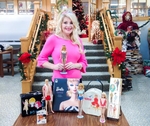 Sharon Austin Holding A 1959 Barbie Featuring The Black And White Swimsuit In Front Of A Sample Of Her Barbie Collection By The Steps To The Library&#8217;s Community Room