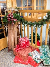 Inside Stair Landing, Upright Wooden Sled, Pile Of Wrapped Gift Boxes With Bows, Garland On Banister